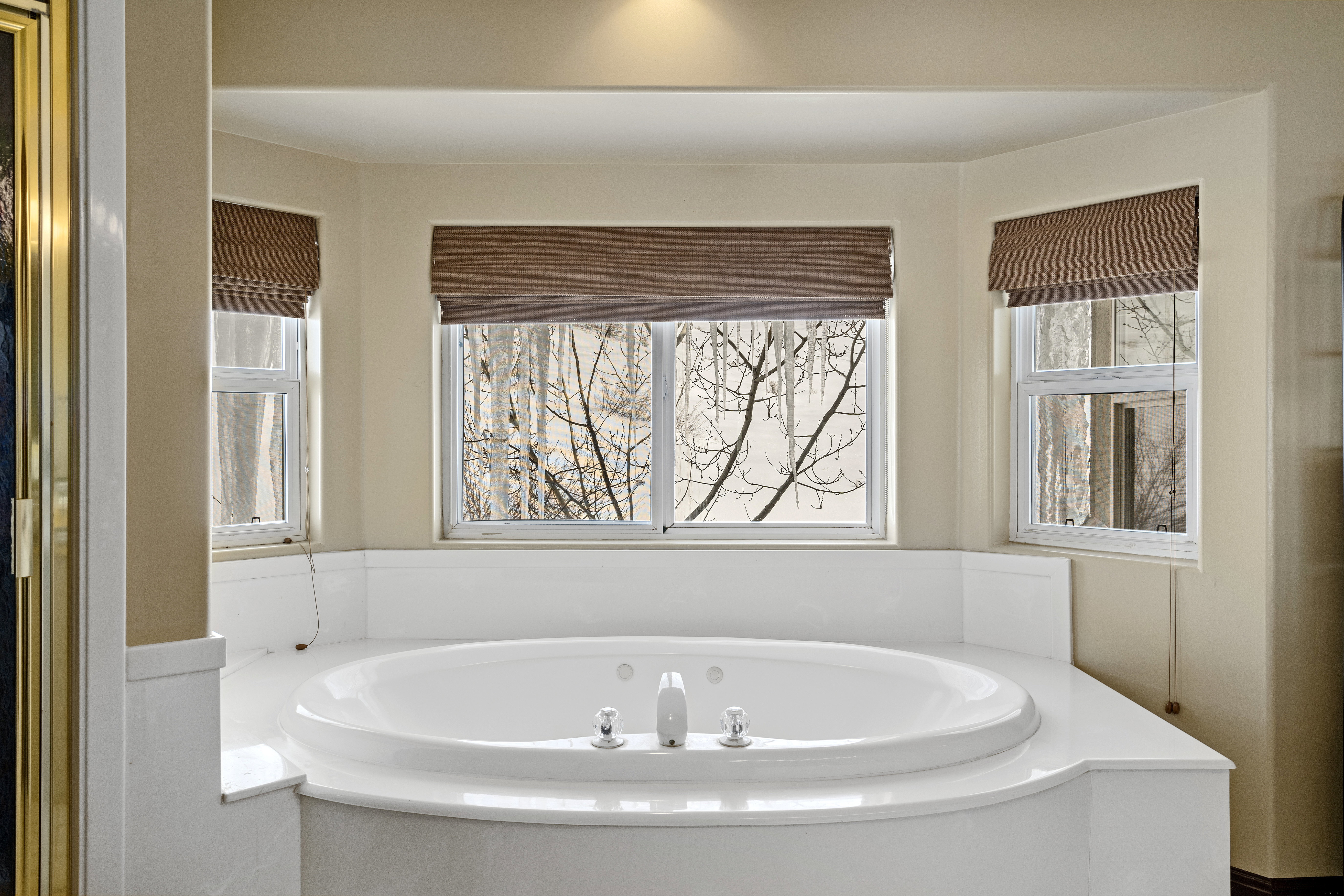 Built-in jetted tub with surrounding white countertop, three windows, and recessed ceiling lighting