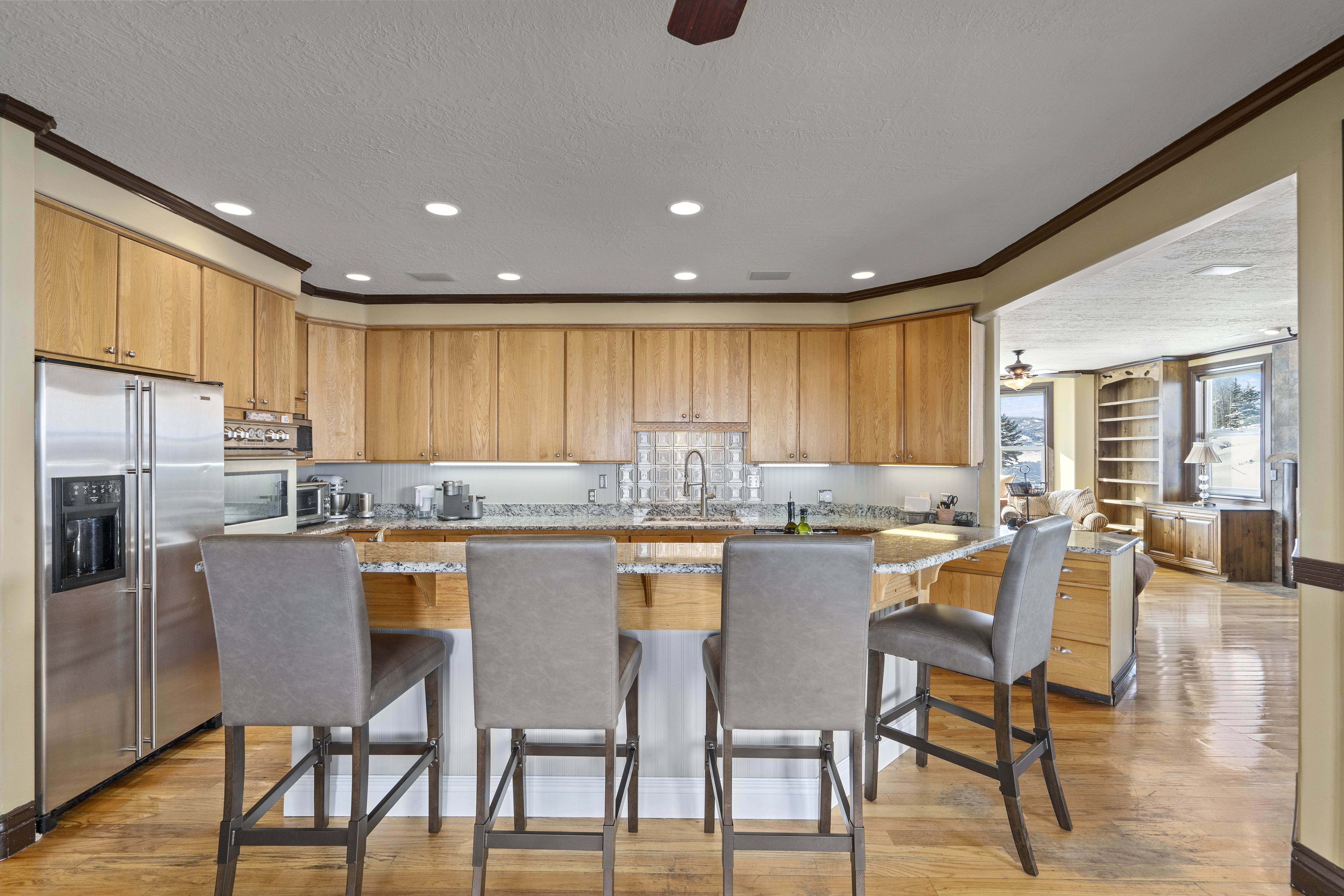 Kitchen featuring light wood cabinetry, stainless steel appliances, and a breakfast bar with stone-finish countertops
