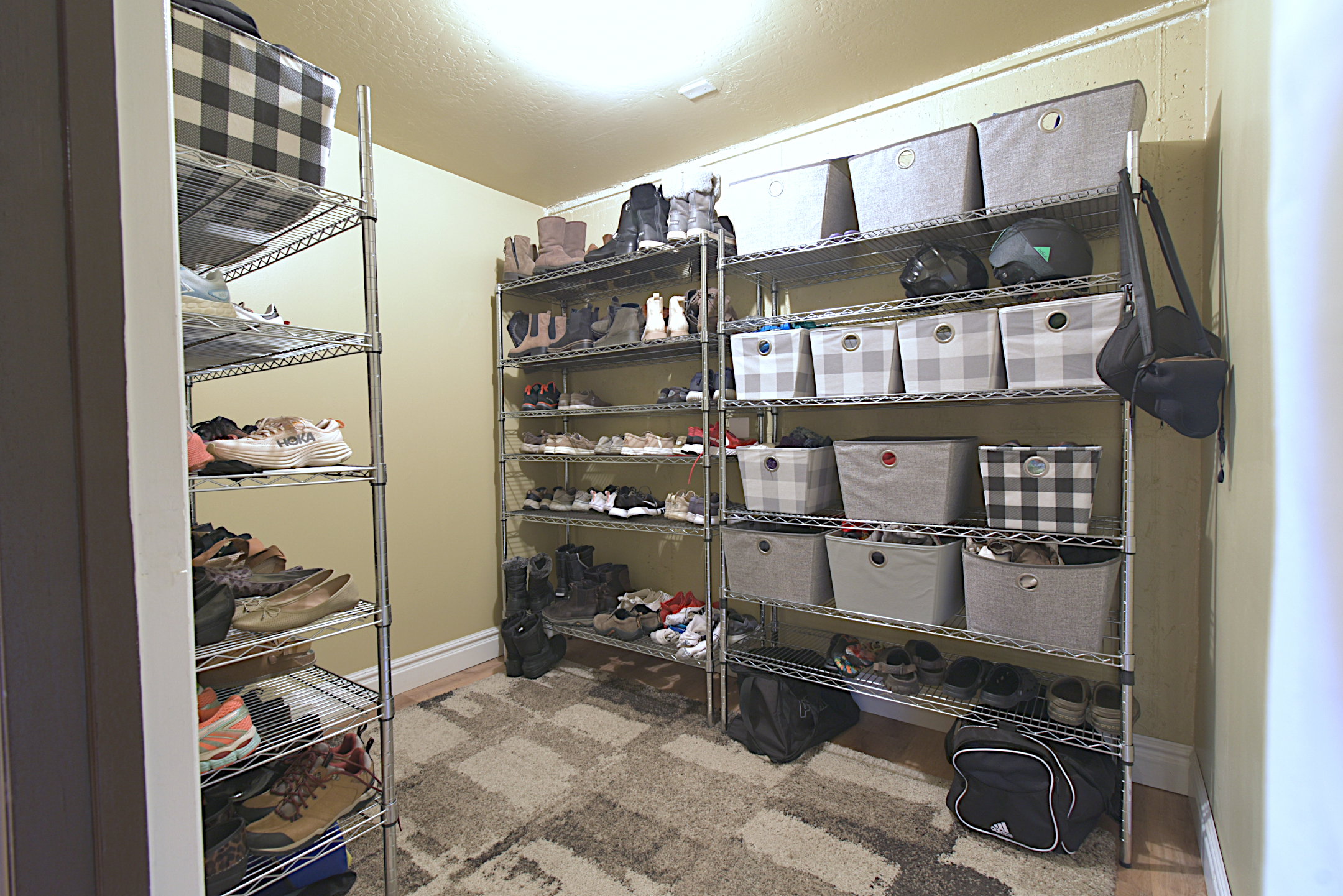 Dedicated storage room featuring multiple chrome wire shelving units, light-colored walls, and a patterned area rug