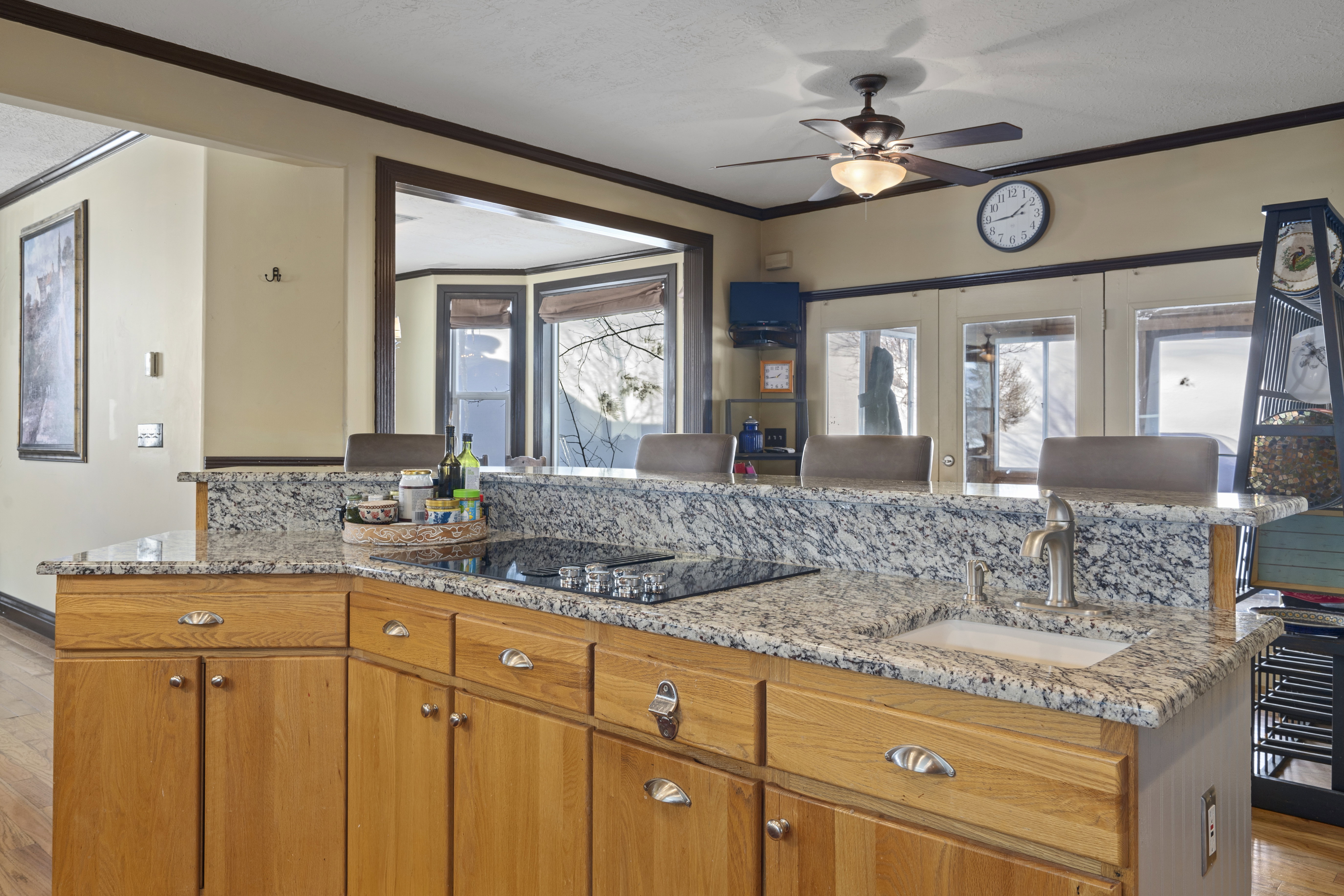 Kitchen featuring light wood cabinetry with silver hardware, speckled countertops, a built-in cooktop, and an undermount sink with a gooseneck faucet