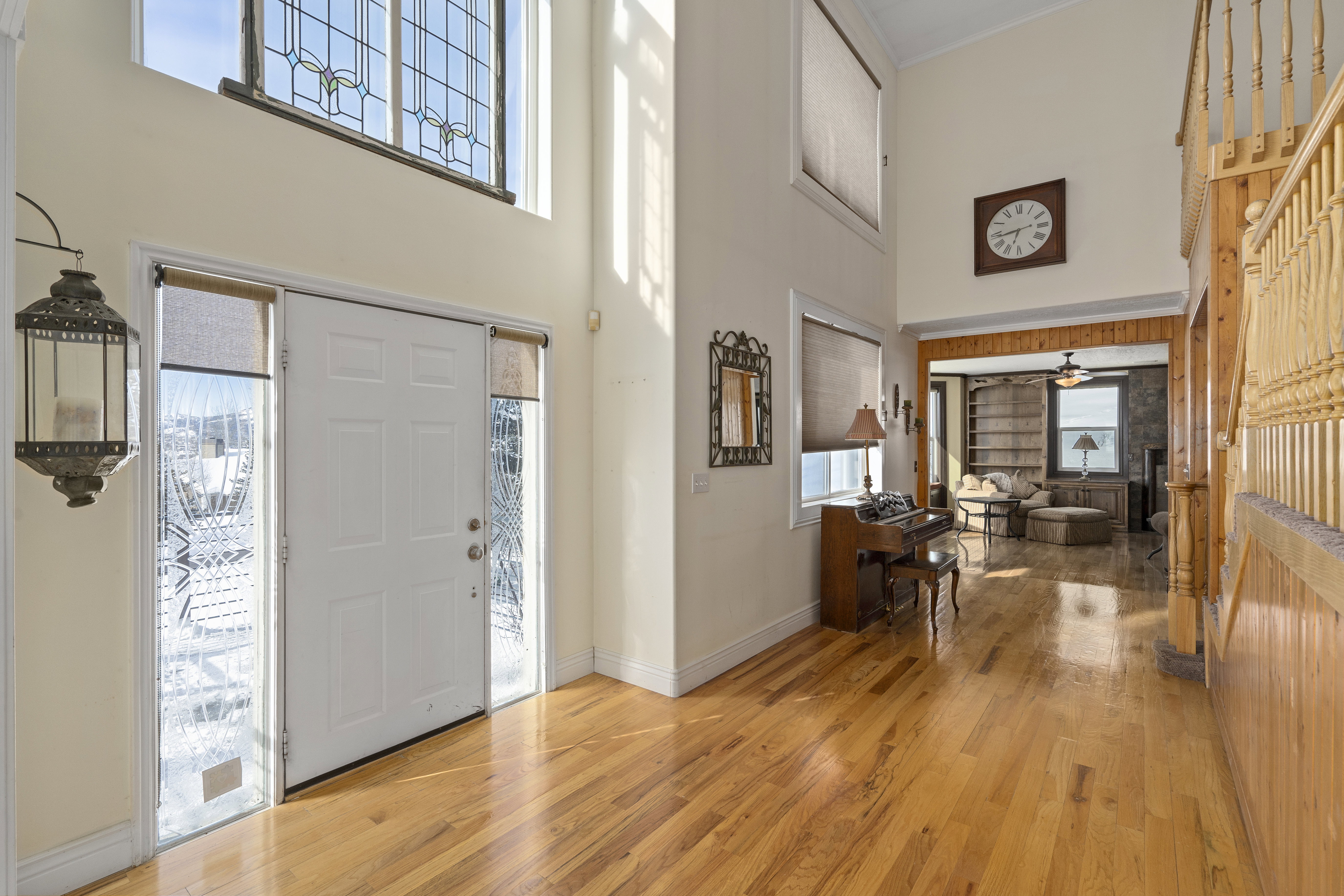 Two-story foyer with transom window featuring leaded glass, hardwood flooring, and a staircase with wood balusters and newel post
