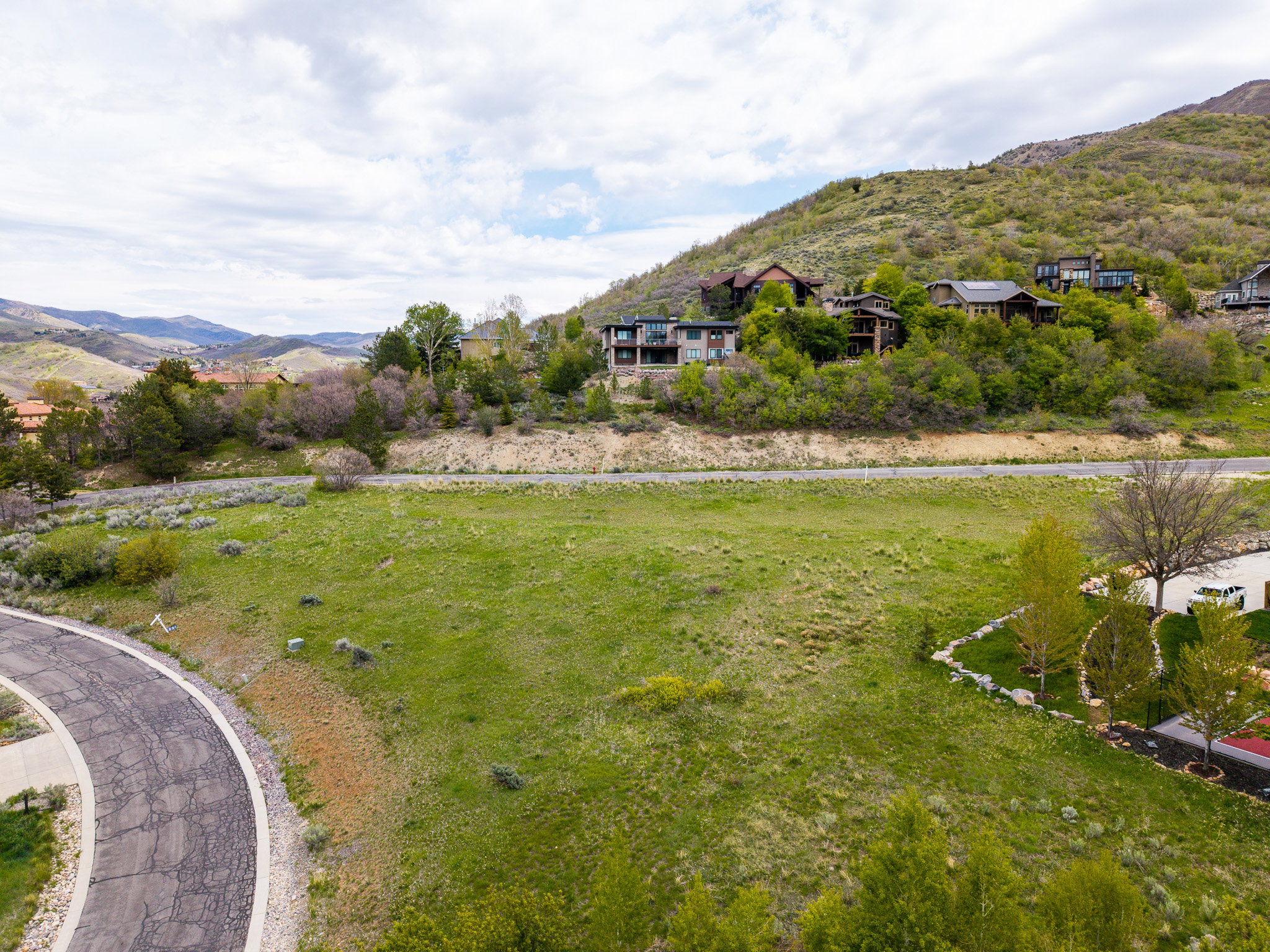 Expansive green lot with established hillside residences in the background