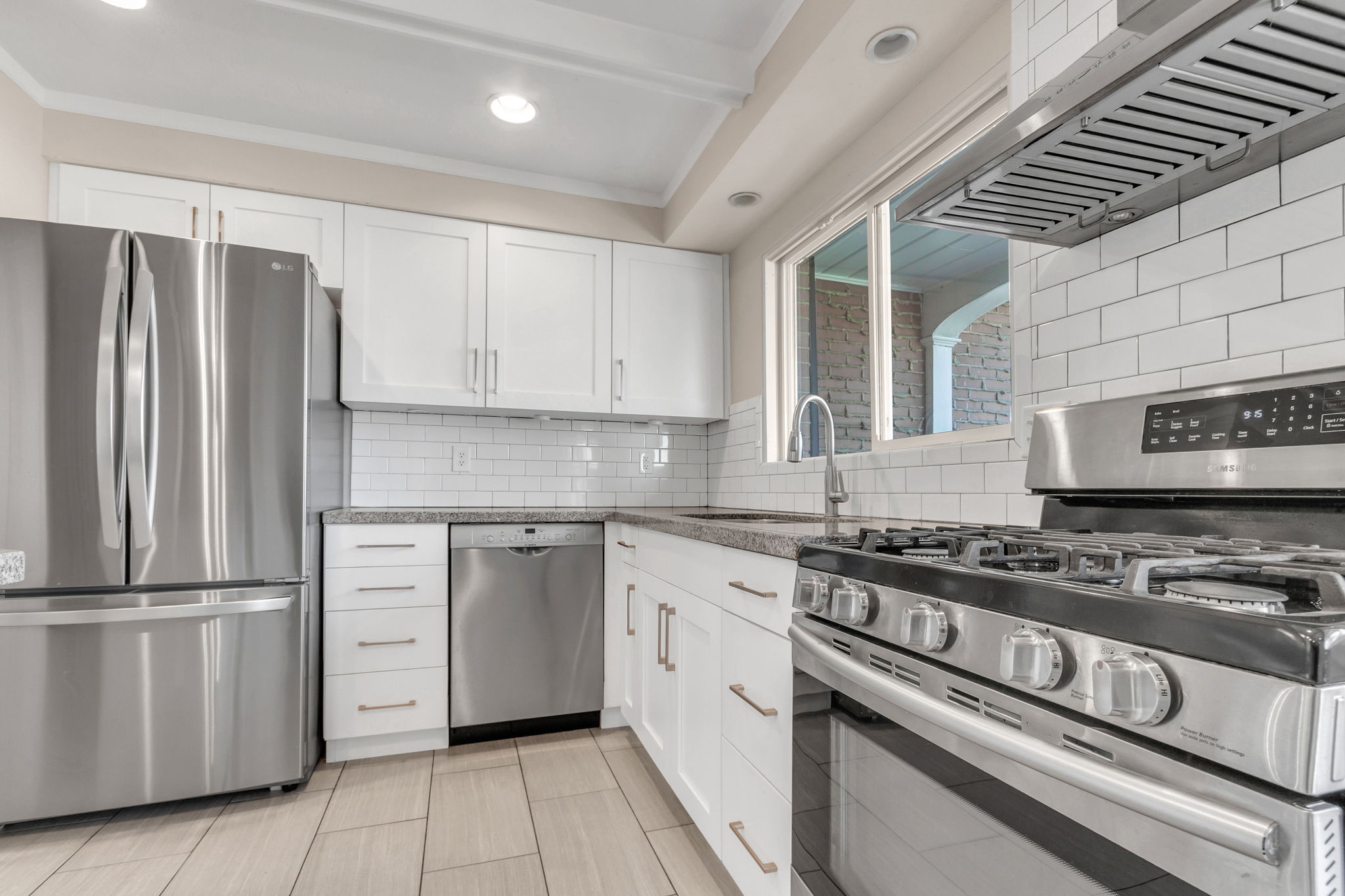 Modern kitchen featuring stainless steel appliances, white subway tile backsplash, white shaker cabinetry, and light-toned wood-finish flooring