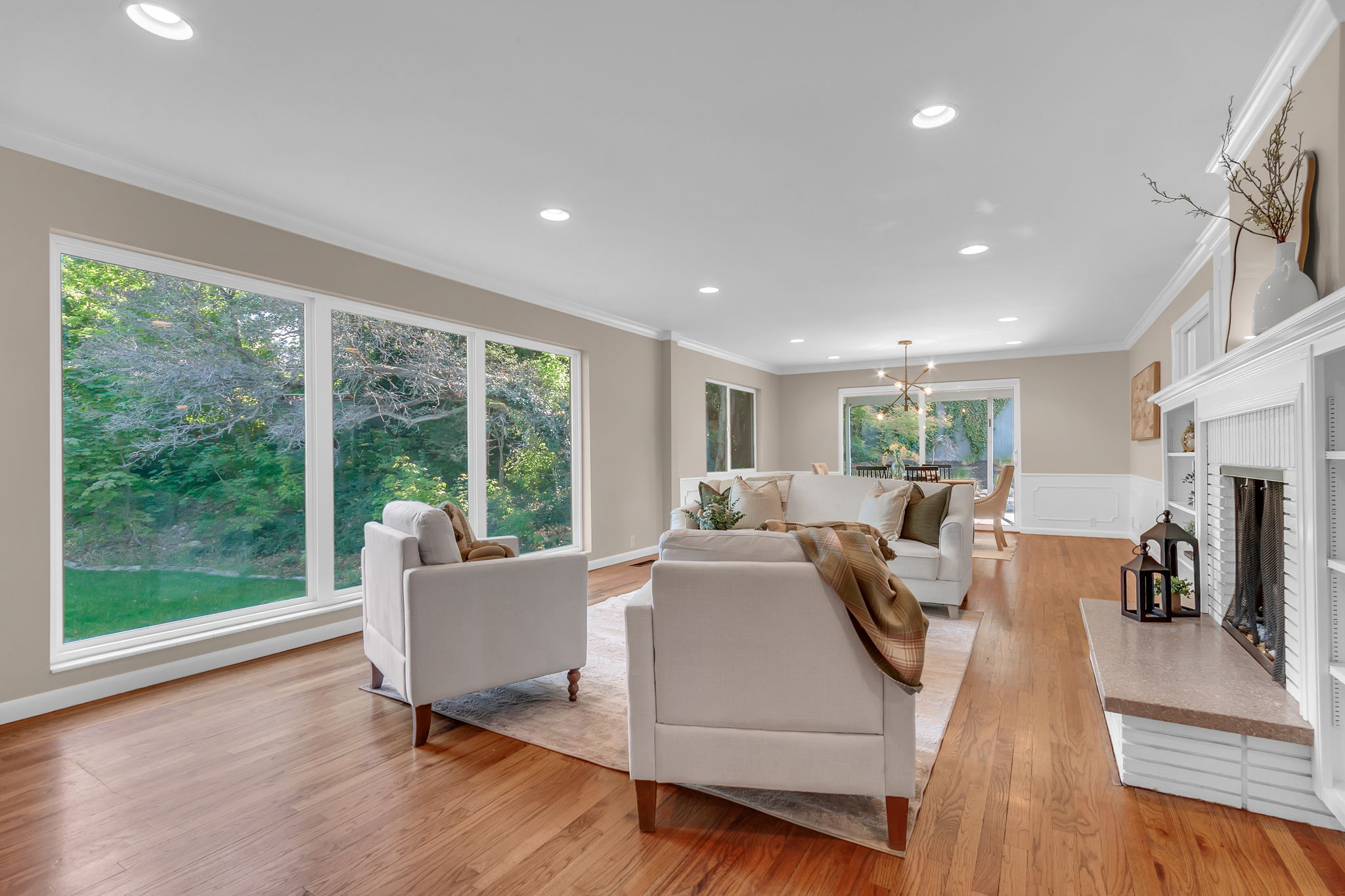 Living area featuring expansive picture windows, wood-finish flooring, recessed lighting, crown molding, and a built-in fireplace with shelving