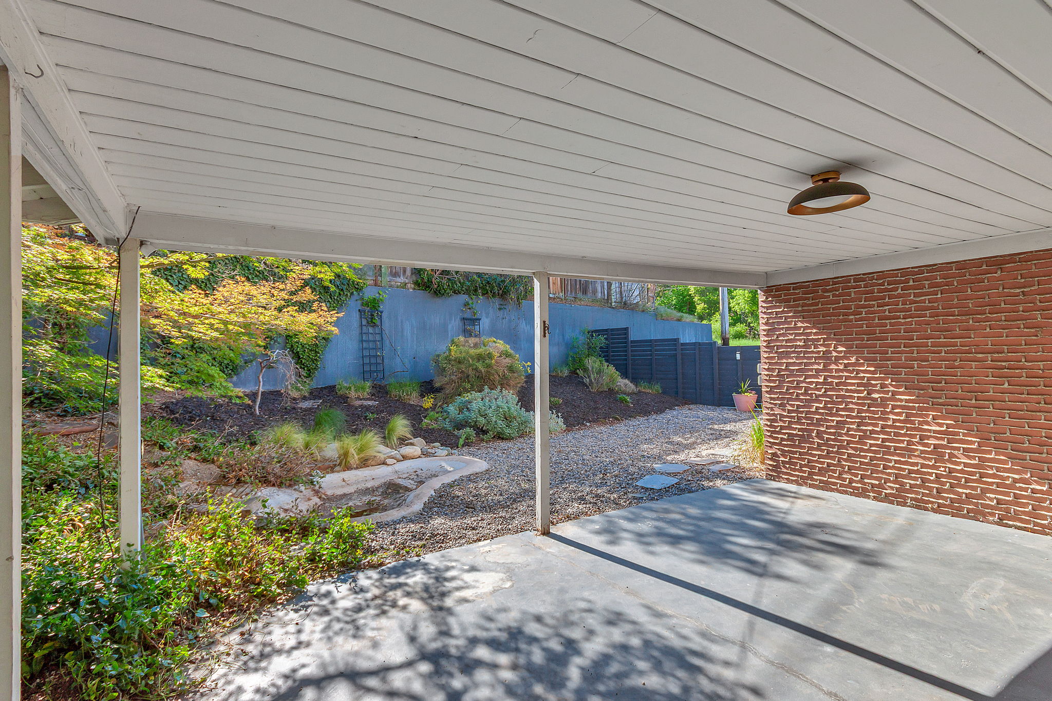 Covered patio area featuring a concrete surface and a brick exterior wall