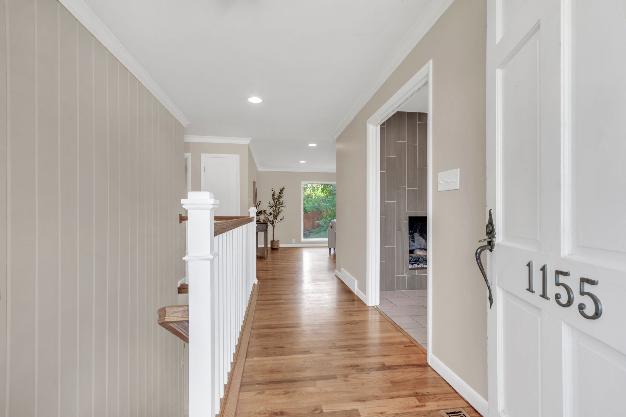 Entryway featuring a paneled door with address numbers, hardwood flooring, recessed lighting, and a staircase with white balusters