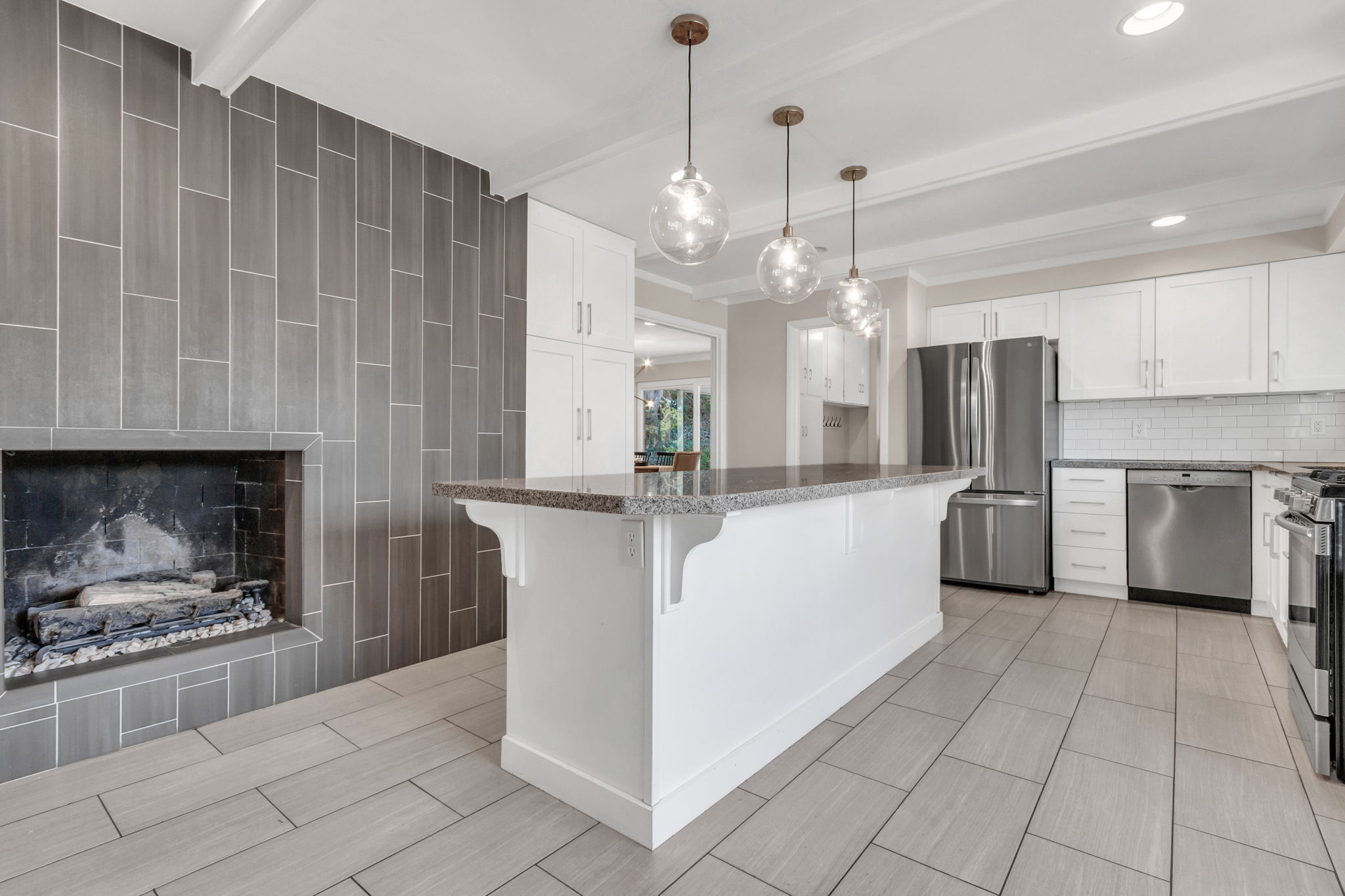 Kitchen featuring a central island with a stone countertop and pendant lighting, stainless steel appliances, white cabinetry, and a tile backsplash