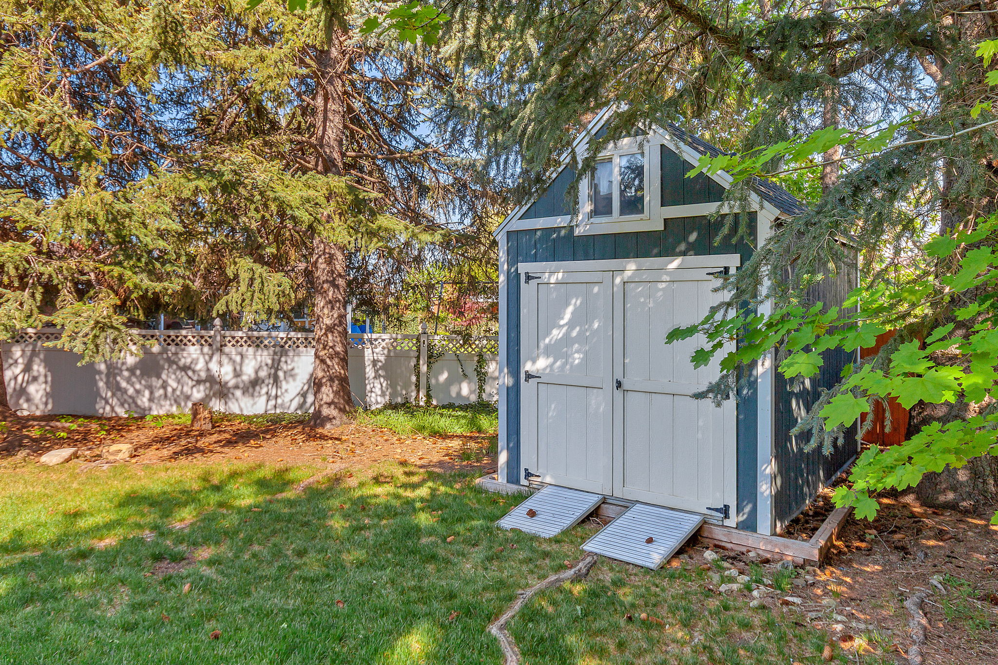 Detached storage shed featuring a gabled roof, dormer window, and double barn doors with metal ramps