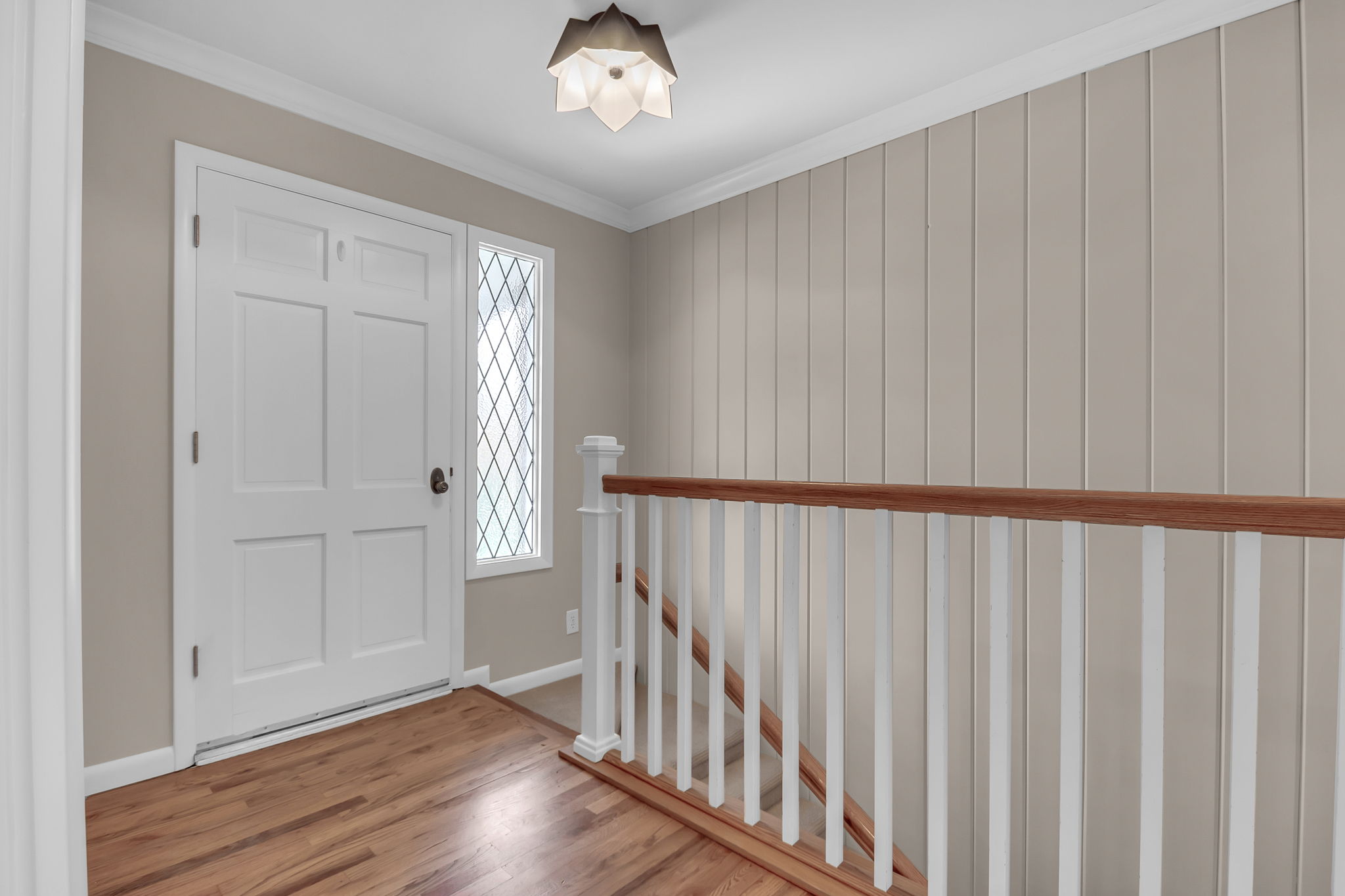 Entryway featuring a white paneled door with dark hardware, a decorative sidelight, and wood-finish flooring