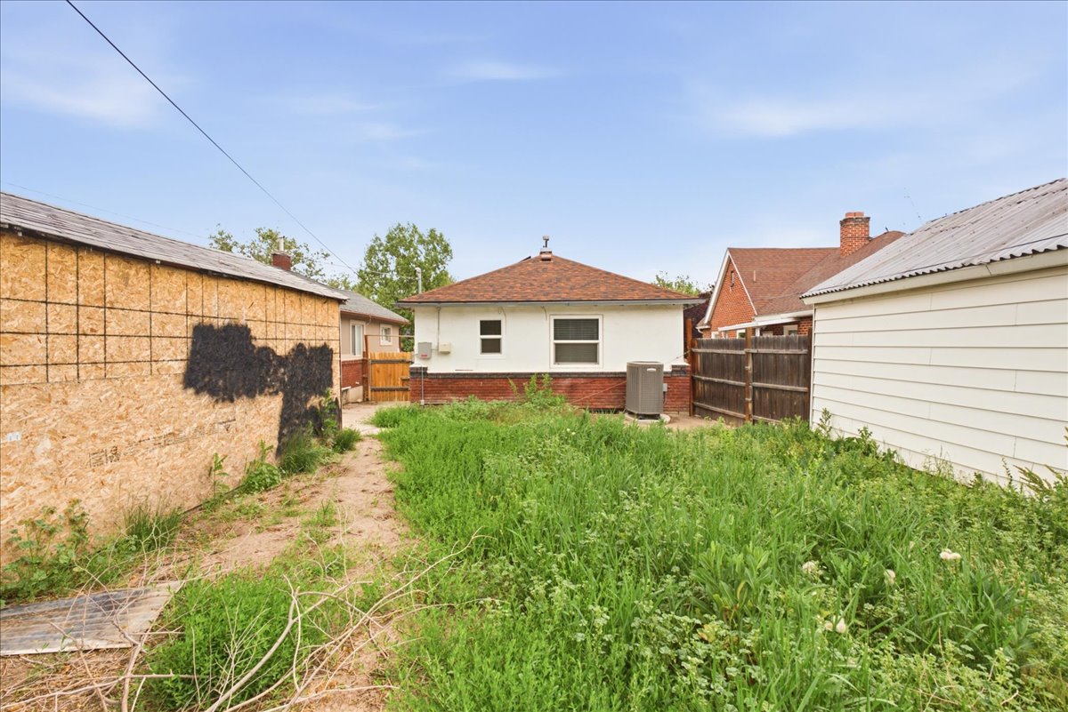 Rear exterior of the property featuring a brick foundation and a brown shingled roof