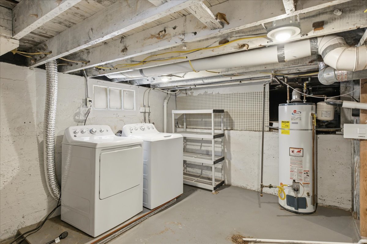 Utility area with a concrete floor, exposed ceiling joists, and a hot water heater
