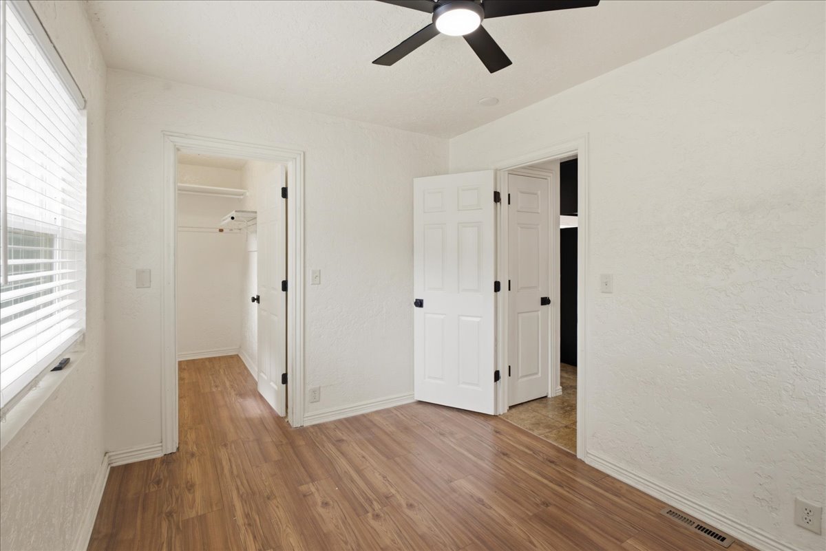 Bedroom featuring wood-finish flooring, white walls, and a ceiling fan with integrated lighting