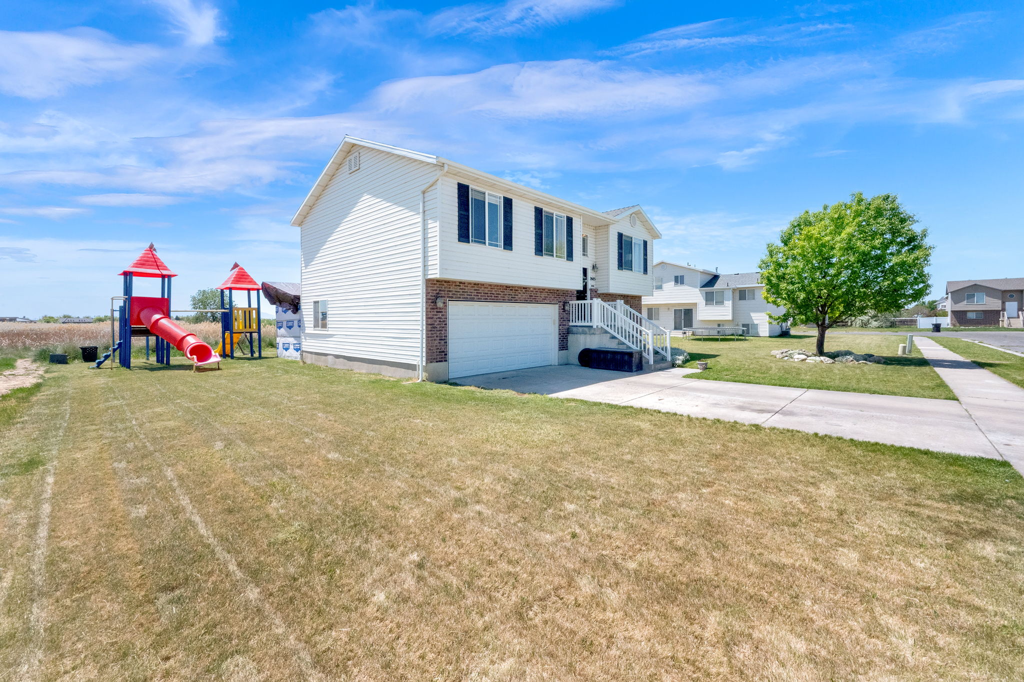 Split-level home featuring a two-car garage, white siding, and brick accents