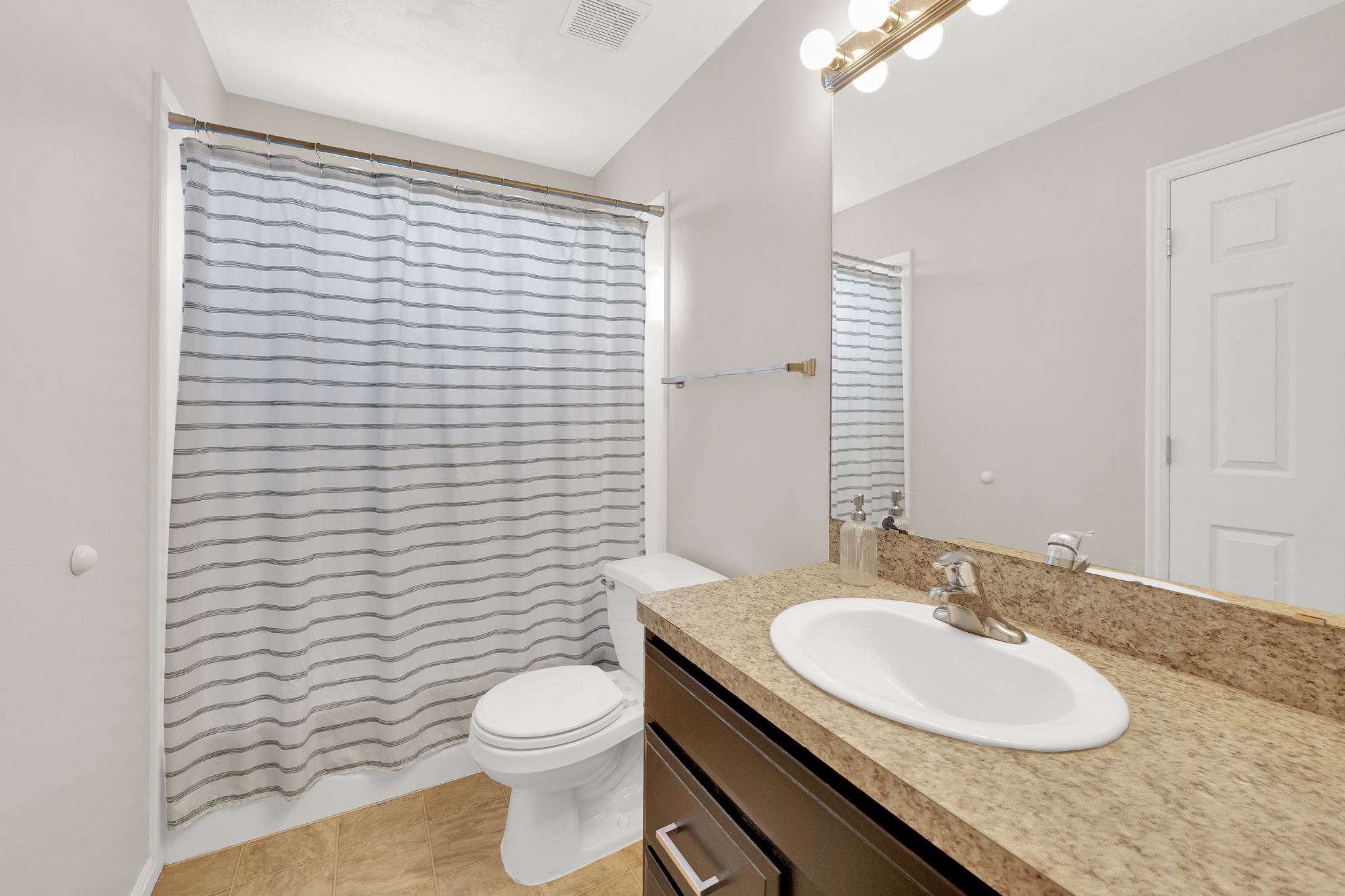 Bathroom featuring a vanity with a light-toned countertop, an integrated sink, and a multi-bulb light fixture