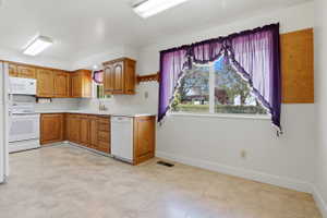 Kitchen featuring light wood cabinetry, white appliances, a white tile backsplash, and a light-toned tile floor