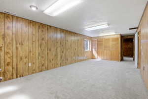 Spacious room featuring light wood paneling, light-colored carpeting, a window with horizontal blinds, and a built-in folding wood screen