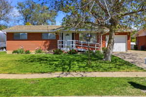 Brick ranch-style residence featuring a well-maintained lawn, a front entry with a ramp, and an attached single-car garage