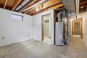 Basement space featuring concrete flooring, white paneled walls, and exposed ceiling joists