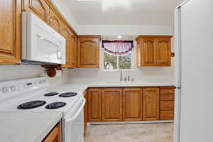 Kitchen featuring wood cabinetry, white countertops, built-in microwave, electric range, and a window above the sink