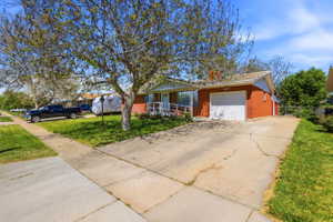 Red brick exterior with white trim, featuring a single-car garage and an accessible ramp leading to the front entry