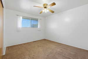 Room with white walls and brown carpet flooring, featuring a window, built-in ceiling fan with light fixture, and a sliding closet door