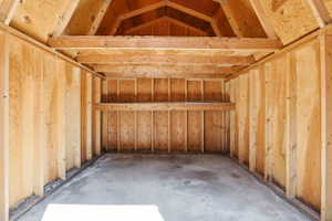 Interior storage space featuring exposed wood framing, an A-frame ceiling, and a concrete floor