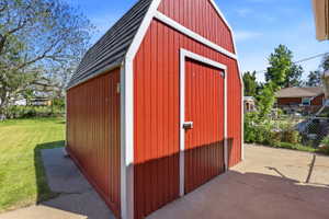 Red exterior storage shed with white trim, a single entry door, and a gambrel-style roof