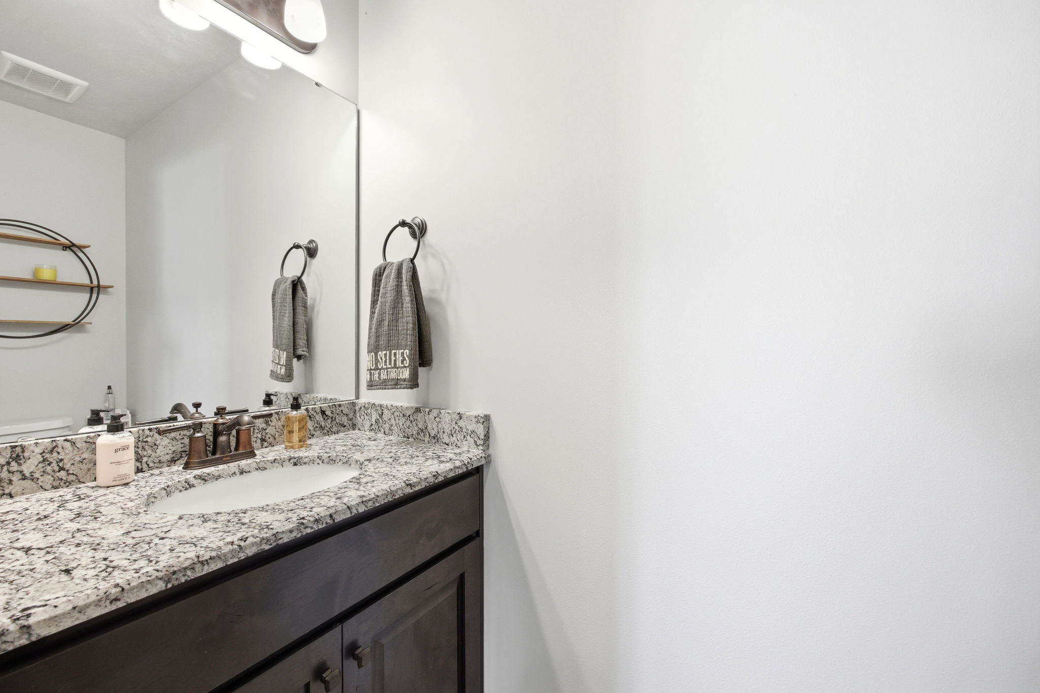 Vanity featuring a stone countertop, an undermount sink, and a bronze-finish faucet