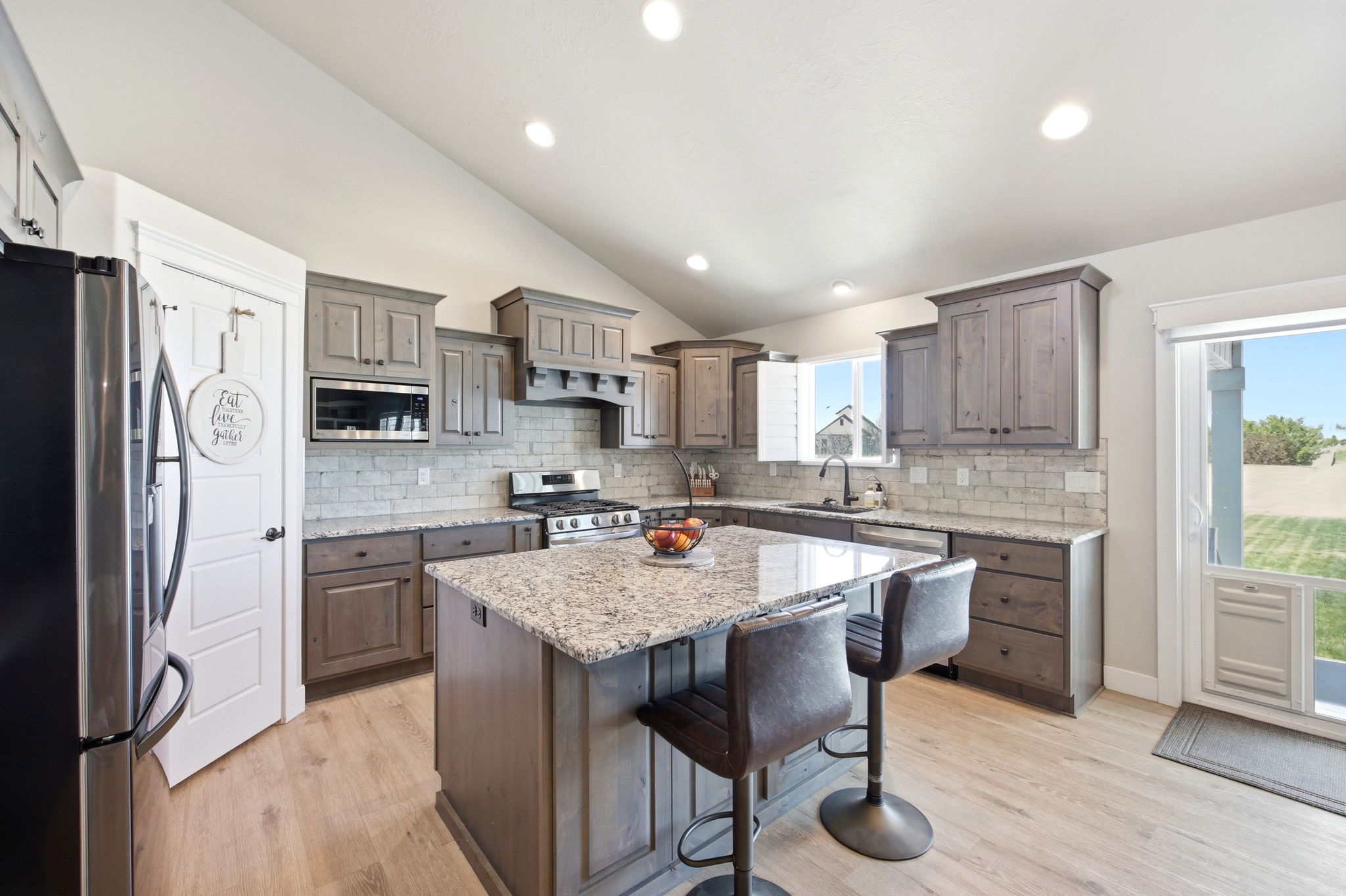 Kitchen featuring a central island with granite countertop, recessed lighting, wood-finish flooring, a full suite of stainless steel appliances, and a tiled backsplash