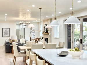 Open-concept living space featuring wood-finish flooring, recessed lighting, and a stone-clad fireplace with a wood mantel