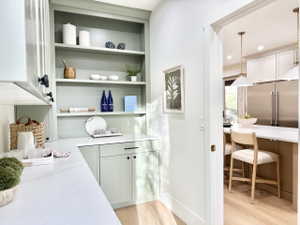 Built-in cabinetry in a soft sage finish with open shelving and lower storage