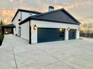 Two-car garage featuring contemporary dark-paneled doors with frosted glass inserts, complemented by traditional wall sconces