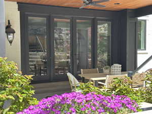 Covered patio featuring a wood-finish ceiling, ceiling fan, and wall-mounted lantern fixture