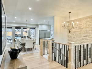 Open-concept interior featuring light wood-finish flooring, a stone accent wall, and a staircase with a black metal and light wood railing