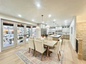 Open-concept dining area featuring wood-finish flooring, a contemporary chandelier, and French doors