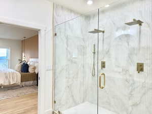 Glass-enclosed shower featuring dual rain shower heads, a handheld shower fixture, and brushed gold hardware