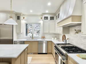 Modern kitchen featuring dual-tone cabinetry, stainless steel appliances, and light wood-finish flooring