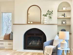 Arched fireplace surround with a dark insert and a light wood-finish mantel
