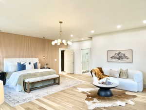 Spacious room featuring wood-finish flooring, a contemporary chandelier, recessed lighting, a slatted accent wall, and an adjacent bath with a glass-enclosed shower