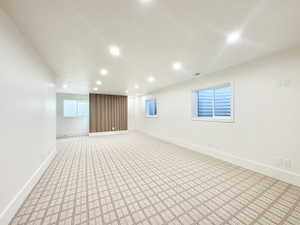 Spacious room featuring patterned carpeting, recessed lighting, and white baseboards