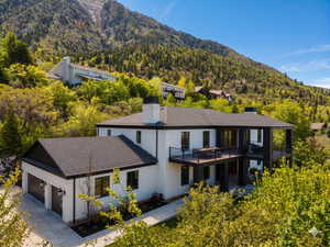Contemporary residence featuring a white stucco exterior with dark trim and a dark shingle roof
