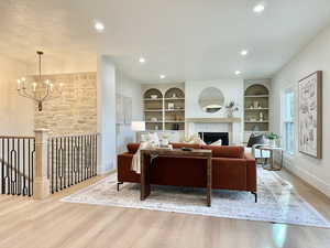 Living area featuring wood-finish flooring, a stone-clad wall, and recessed lighting