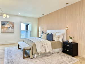 Bedroom featuring a horizontal slatted accent wall, light wood-finish flooring, recessed lighting, and a window with white trim