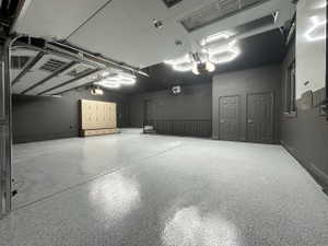 Spacious garage featuring a durable epoxy floor finish, integrated overhead lighting, built-in cabinetry for organized storage, and a convenient interior access point