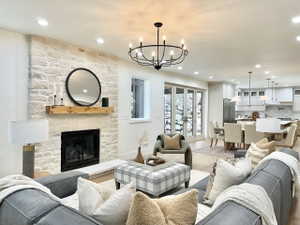 Expansive living area featuring a stone fireplace with a wood-finish mantel, recessed lighting, and a contemporary chandelier