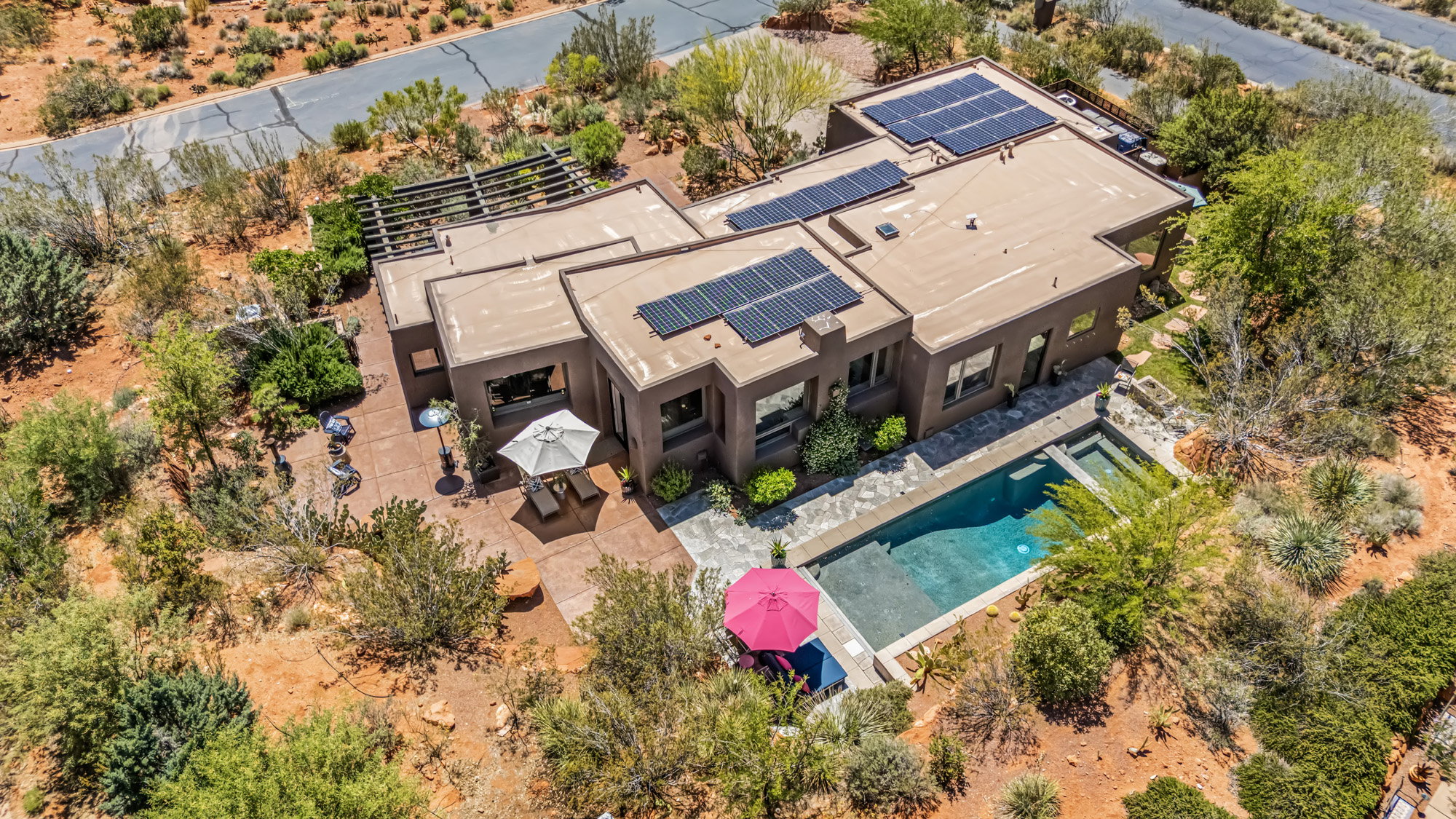 Contemporary architecture with a flat roof, integrated solar panels, a rectangular swimming pool, and an adjacent patio with a pergola