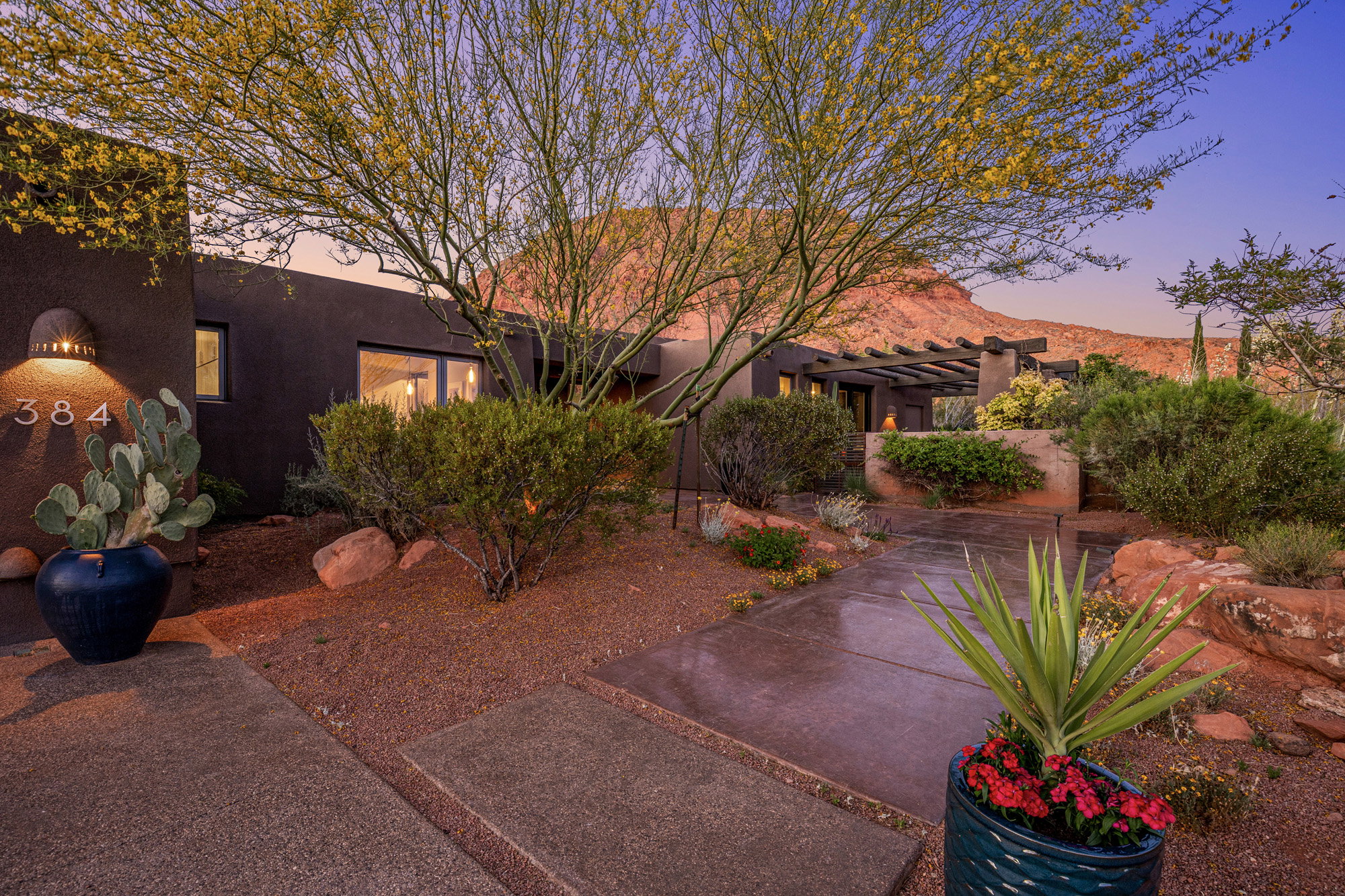 Southwestern-style residence featuring a dark stucco exterior and a pergola-covered patio