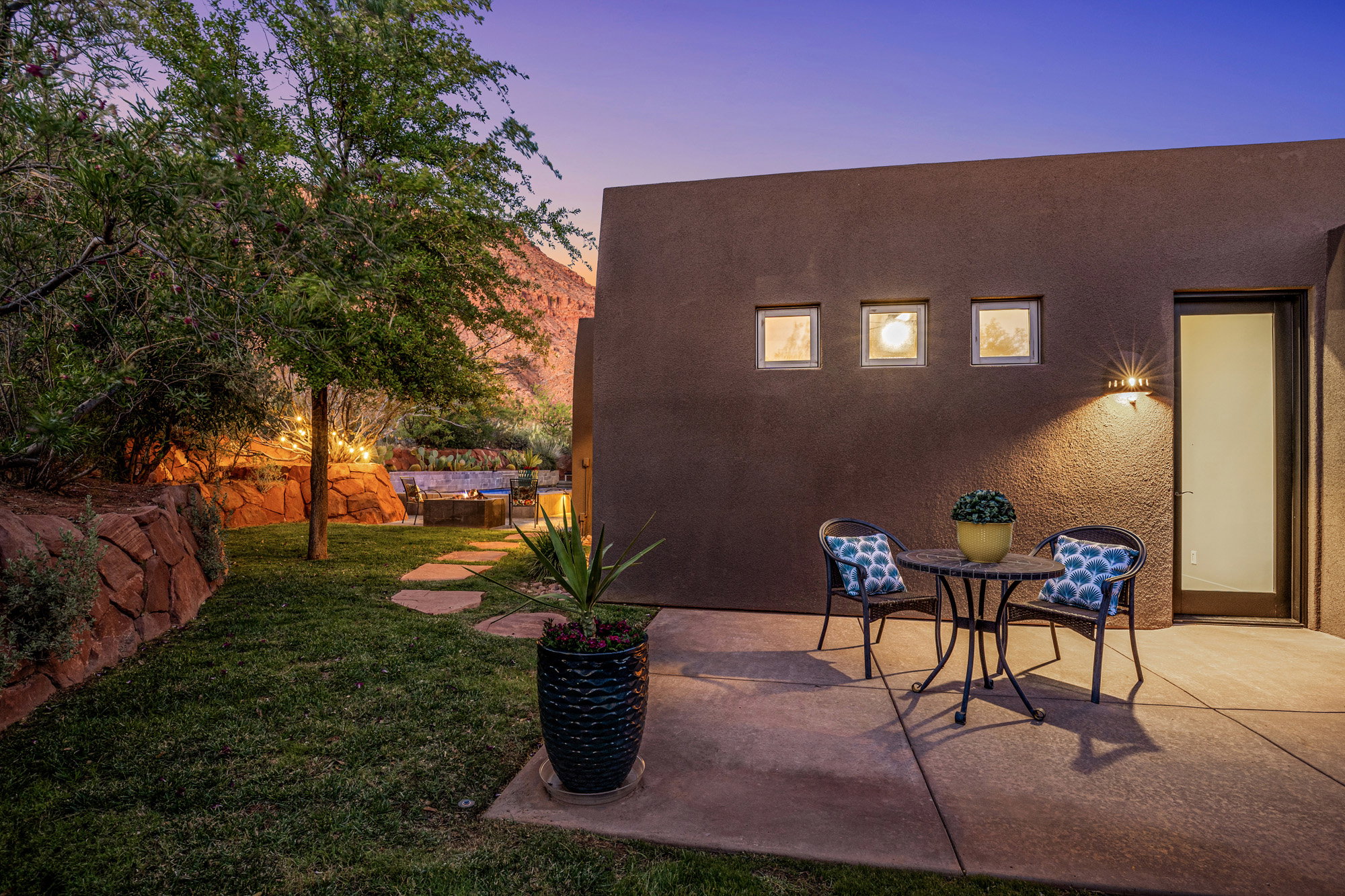 Exterior patio featuring a stucco finish, three square window accents, and a contemporary outdoor sconce