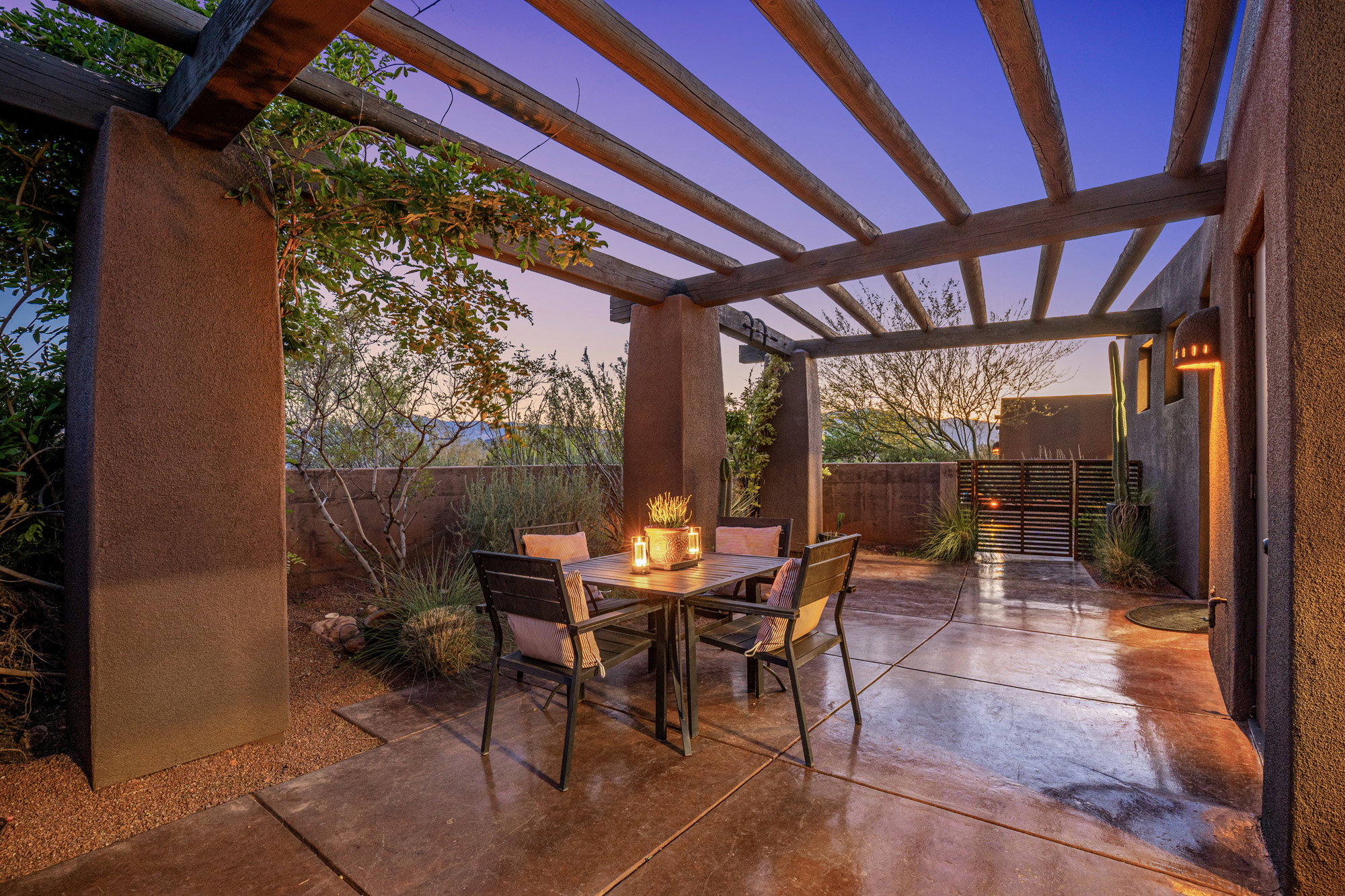 Paved patio featuring a wood pergola, stucco columns, and an integrated wall lantern