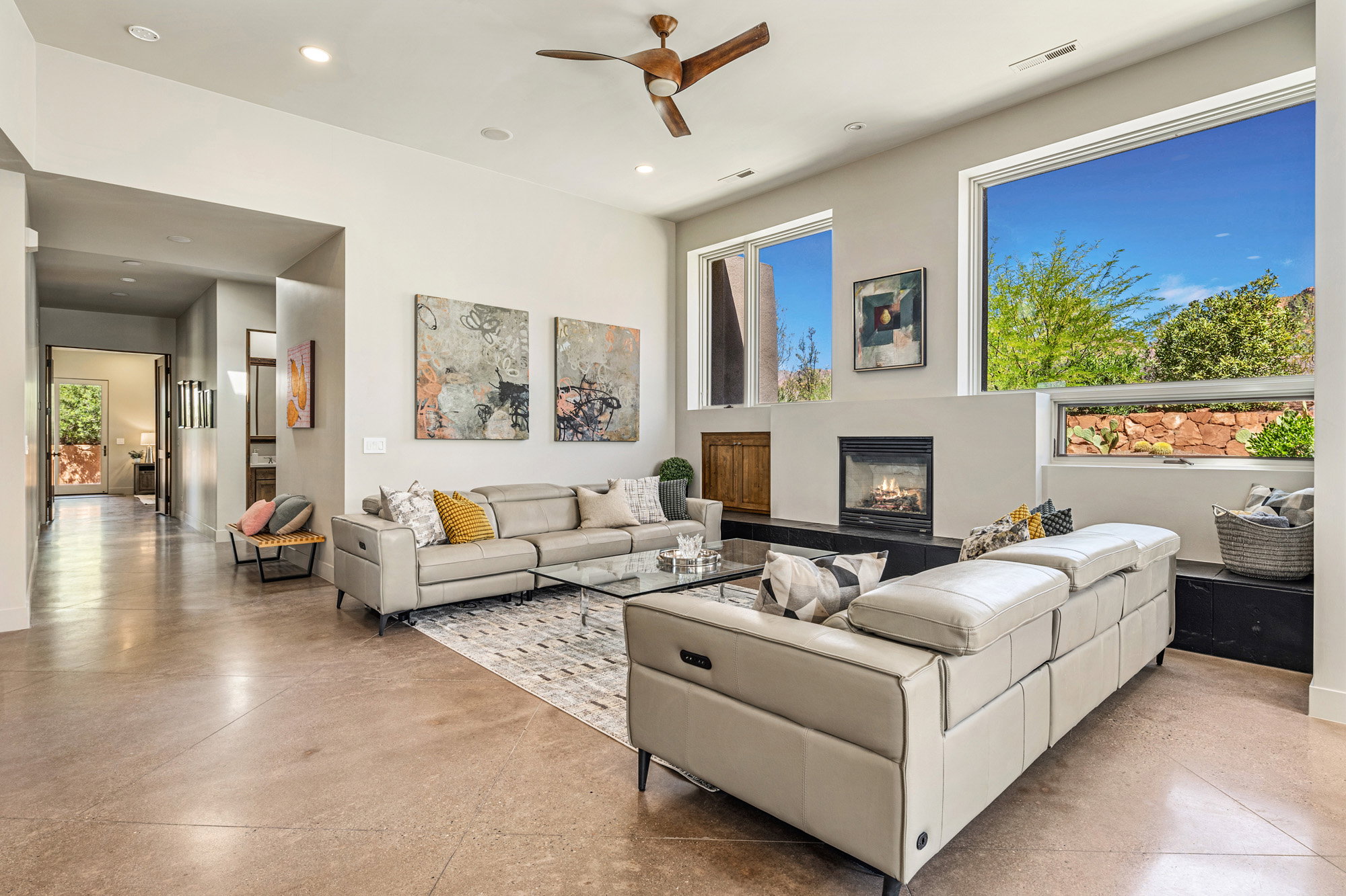 Spacious living area featuring high ceilings, large floor-to-ceiling windows, a built-in fireplace, and polished concrete flooring